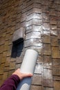 WomanÃ¢â¬â¢s hand shaking moss killer granules on the ridgeline of a house with asphalt shingle roof